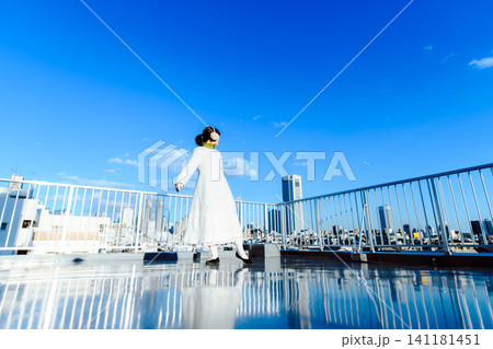 屋上で踊るように歩く女性、青空と街並み 屋上で踊るように歩く女性、青空と街並み 141181451
