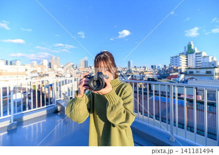 カメラを持つ女性、街並みを背景に カメラを持つ女性、街並みを背景に 141181494