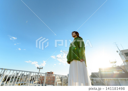 街並みを望む女性、太陽の光を浴びて 街並みを望む女性、太陽の光を浴びて 141181498