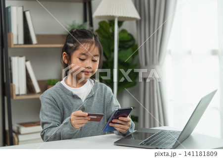Young Asian girl using smartphone and holding credit card for online shopping at home with laptop on table in comfortable living room setting Young Asian girl using smartphone and holding credit card for online shopping at home with laptop on table in comfortable living room setting 141181809