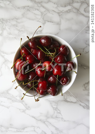 Plump Sweet Cherries Piled High in a Minimalist White Bowl over Veined Marble Backdrop Plump Sweet Cherries Piled High in a Minimalist White Bowl over Veined Marble Backdrop 141182308