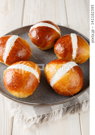 luscious Roman Maritozzi are incredibly light, soft sweet buns filled with loads of perfectly whipped cream close-up in a plate. Vertical 141182395
