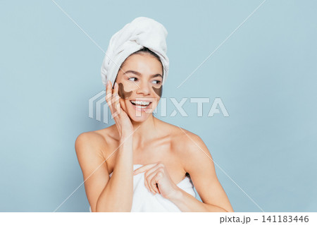 Smiling woman with face mask and towel, light blue background 141183446