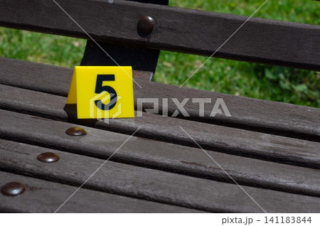 One yellow crime scene marker on a wooden bench One yellow crime scene marker on a wooden bench 141183844