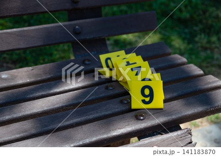 A set of yellow crime scene markers lies on a wooden bench A set of yellow crime scene markers lies on a wooden bench 141183870