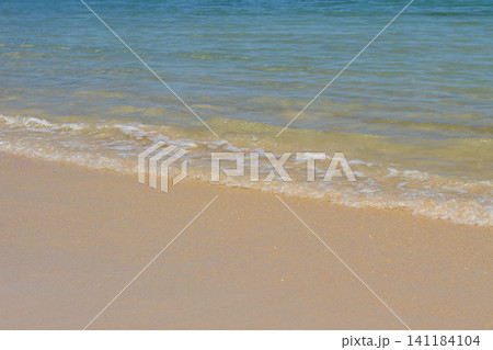 穏やかな波が優しく寄せる夏の砂浜と透き通った海面 141184104