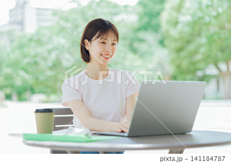 テラスでパソコンを使う若い女性 テラスでパソコンを使う若い女性 141184787