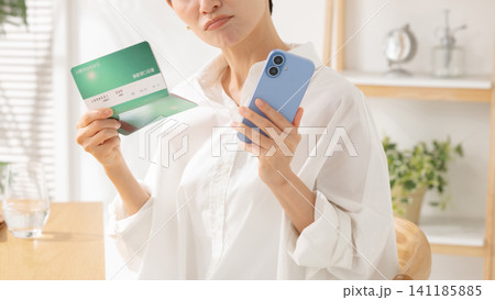 通帳を見て悩むミドル女性 通帳を見て悩むミドル女性 141185885