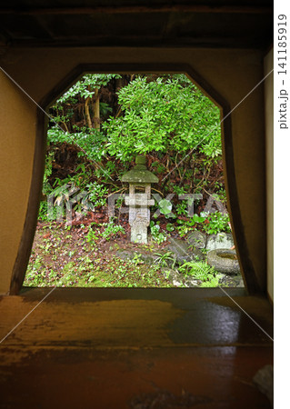 火灯窓から望む美しい日本庭園 額縁のように切り取られた新緑の木々と佇む石灯籠が織りなすわびさびの風情 火灯窓から望む美しい日本庭園 額縁のように切り取られた新緑の木々と佇む石灯籠が織りなすわびさびの風情 141185919