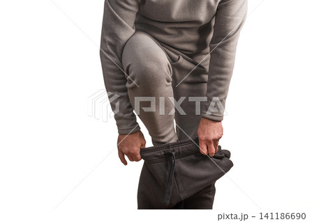 Adult man wears black sports trousers over grey thermal underwear. Adult man wears black sports trousers over grey thermal underwear. 141186690