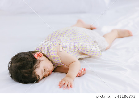 ベッドでお昼寝する1歳のかわいい女の子 141186873