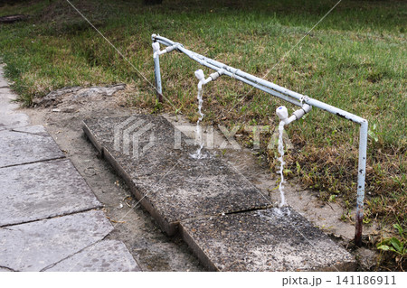 Outdoor foot wash faucet pouring water onto concrete platform, Outdoor foot wash faucet pouring water onto concrete platform, 141186911