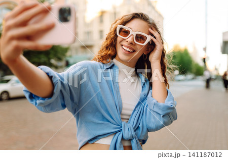 Beautiful woman traveler using phone, taking selfie, walking on the old town street. Blogging Beautiful woman traveler using phone, taking selfie, walking on the old town street. Blogging 141187012
