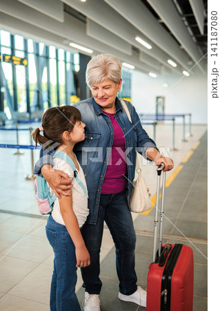 Grandmother and child traveling together at airport terminal Grandmother and child traveling together at airport terminal 141187080