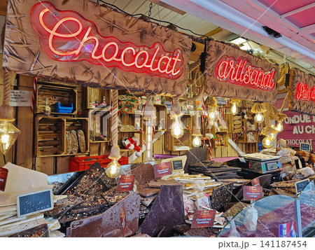 Paris, France - December 10, 2025: rustic vendor stall showcases large slabs of artisanal French chocolate in dark, milk, and white varieties. Festive holiday display at the Tuileries Christmas Market Paris, France - December 10, 2025: rustic vendor stall showcases large slabs of artisanal French chocolate in dark, milk, and white varieties. Festive holiday display at the Tuileries Christmas Market 141187454