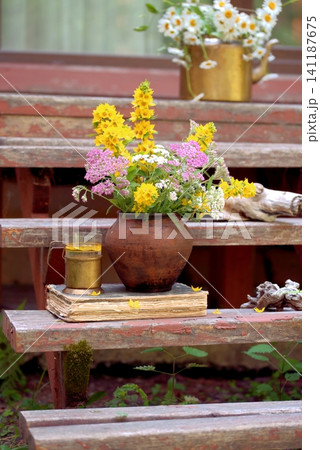 Vintage still life on an old wooden porch with wildflowers and an old book Vintage still life on an old wooden porch with wildflowers and an old book 141187675