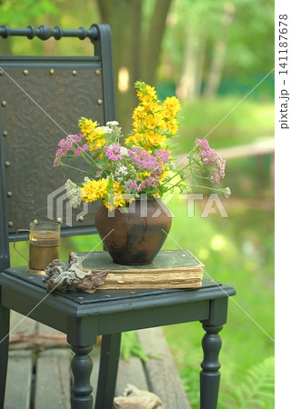 Vintage still life on an old chair with wildflowers and an old book. Vintage still life on an old chair with wildflowers and an old book. 141187678