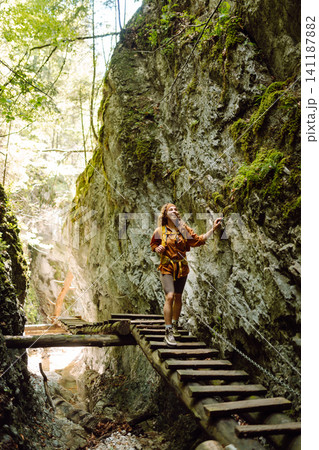 A woman traveler with a bright backpack travels through the mountains on a hiking trail. Adventures. A woman traveler with a bright backpack travels through the mountains on a hiking trail. Adventures. 141187882