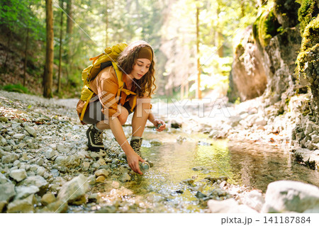 Traveler walks along forest hiking trail in mountains against the backdrop of mountain nature. Traveler walks along forest hiking trail in mountains against the backdrop of mountain nature. 141187884