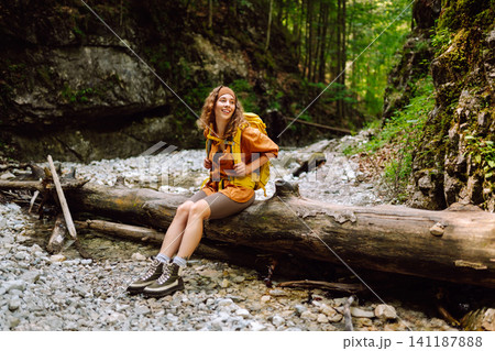 A traveler walks along forest hiking trail in mountains on a sunny day. Outdoor recreation concept. A traveler walks along forest hiking trail in mountains on a sunny day. Outdoor recreation concept. 141187888
