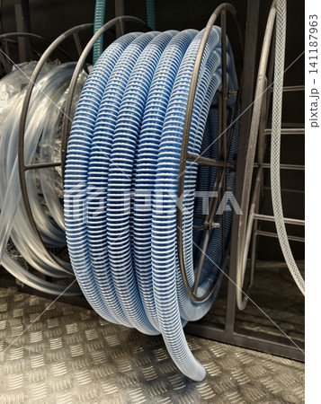 Blue corrugated hose displayed in a coiled form is positioned on store racks among general construction materials Blue corrugated hose displayed in a coiled form is positioned on store racks among general construction materials 141187963