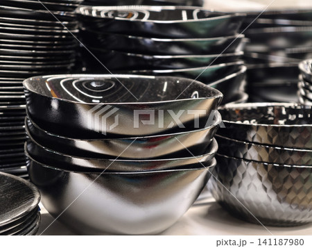 Black matte salad bowls stacked evenly on store shelving with classic rounded design for everyday use Black matte salad bowls stacked evenly on store shelving with classic rounded design for everyday use 141187980