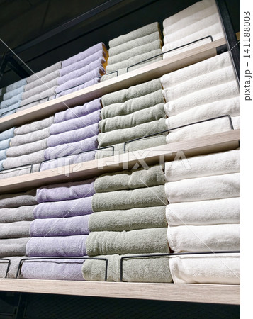 Assorted cotton towels in multiple colors stacked on large shelves in hypermarket Assorted cotton towels in multiple colors stacked on large shelves in hypermarket 141188003