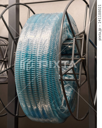 Light blue corrugated hose coiled and wrapped in plastic packaging is stored on a warehouse shelf among construction and utility supply products Light blue corrugated hose coiled and wrapped in plastic packaging is stored on a warehouse shelf among construction and utility supply products 141188021