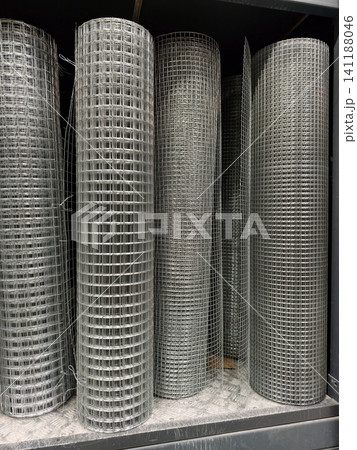 Galvanized welded metal mesh rolled into large coils stored inside a construction warehouse Galvanized welded metal mesh rolled into large coils stored inside a construction warehouse 141188046