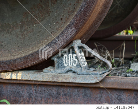 Metal brake chock securing stationary position of train wheel on industrial railway line Metal brake chock securing stationary position of train wheel on industrial railway line 141188047