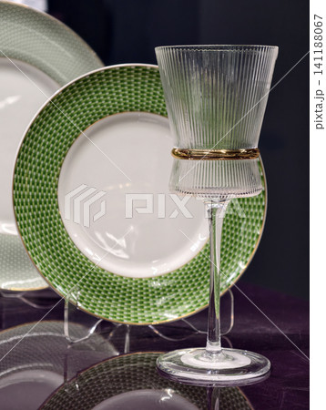 Elegant wine glass shining with green plates softly blurred behind on a luxury table 141188067