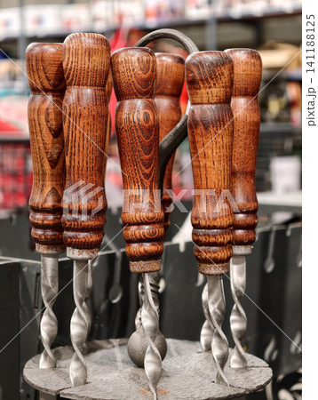 Stainless metal skewers with wooden grip handles displayed in retail shop showing barbecue cooking tools prepared for grilling and outdoor food serving use Stainless metal skewers with wooden grip handles displayed in retail shop showing barbecue cooking tools prepared for grilling and outdoor food serving use 141188125