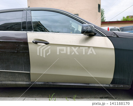 Urban vehicle with one front door in different color after collision repair. Passenger car with one light front door indicating recent replacement or repair Urban vehicle with one front door in different color after collision repair. Passenger car with one light front door indicating recent replacement or repair 141188170