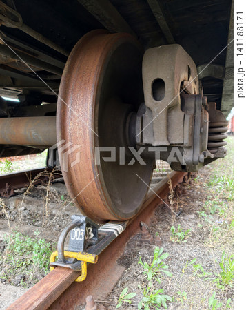Railway brake wedge positioned under train wheel securing freight transport on tracks Railway brake wedge positioned under train wheel securing freight transport on tracks 141188171
