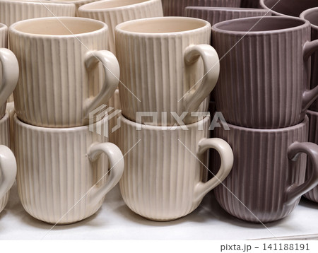 Ceramic cups displayed in supermarket shelving forming practical kitchenware assortment suitable for everyday dining and home use Ceramic cups displayed in supermarket shelving forming practical kitchenware assortment suitable for everyday dining and home use 141188191