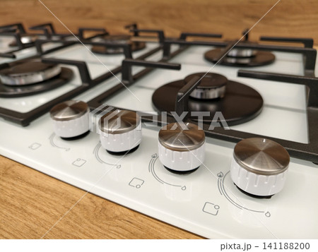 Kitchen white built in gas range showing detailed control knobs in a retail warehouse ideal for modern cooking setups Kitchen white built in gas range showing detailed control knobs in a retail warehouse ideal for modern cooking setups 141188200