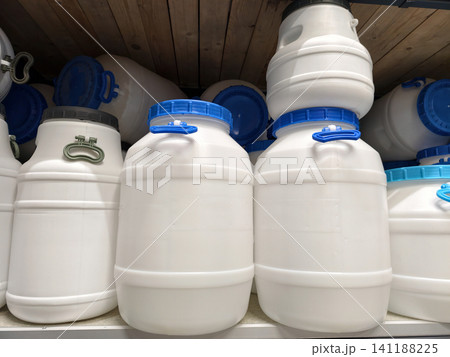 A display of large white plastic barrels on shelves in a home improvement store, ready for purchase 141188225