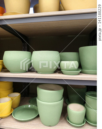 Green ceramic plant pots with saucers of various sizes arranged neatly on shelves in a shopping store plant department Green ceramic plant pots with saucers of various sizes arranged neatly on shelves in a shopping store plant department 141188229
