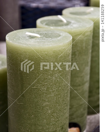 Green pillar candles shown in close up, highlighting wax texture and rich color, suitable for stylish interior decoration and ambient home styling Green pillar candles shown in close up, highlighting wax texture and rich color, suitable for stylish interior decoration and ambient home styling 141188259