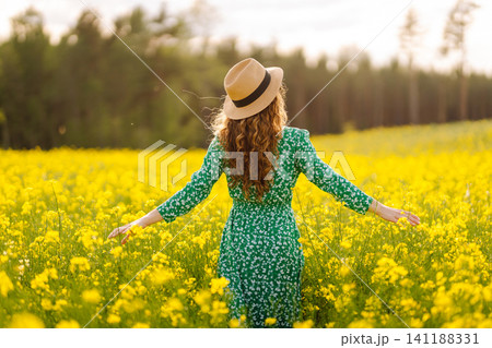 Beautiful woman walking flowering field gently touch yellow flowers. Fashion, summer lifestyle. Beautiful woman walking flowering field gently touch yellow flowers. Fashion, summer lifestyle. 141188331