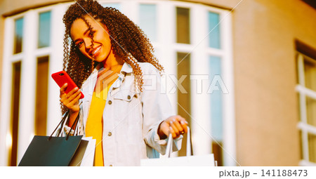 Young woman with shopping bags walking on street. Sale, shopping and happy people concept. Young woman with shopping bags walking on street. Sale, shopping and happy people concept. 141188473
