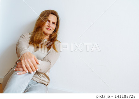 Portrait middle-aged blonde woman sitting on floor 141188728