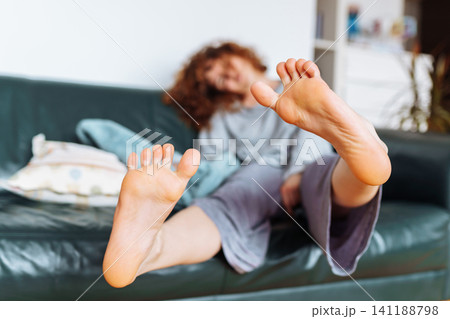 young red-haired woman relaxing on leather sofa young red-haired woman relaxing on leather sofa 141188798
