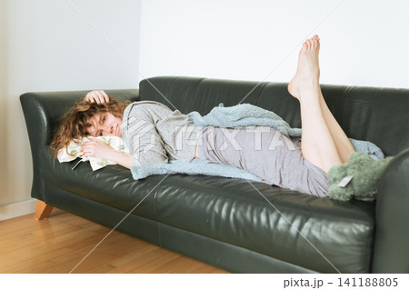 young red-haired woman relaxing on leather sofa young red-haired woman relaxing on leather sofa 141188805