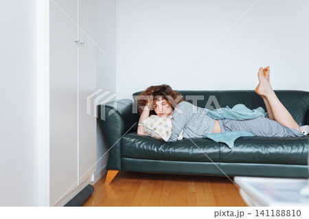 young red-haired woman relaxing on leather sofa young red-haired woman relaxing on leather sofa 141188810