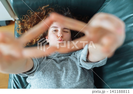 young red-haired woman relaxing on leather sofa 141188811