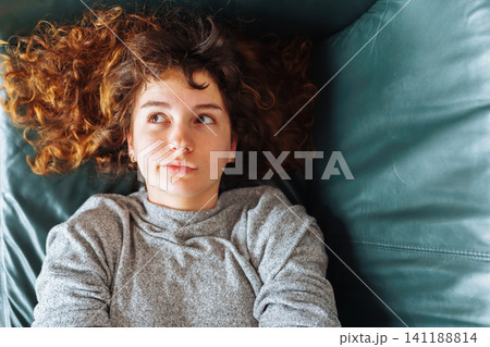 young red-haired woman relaxing on leather sofa young red-haired woman relaxing on leather sofa 141188814