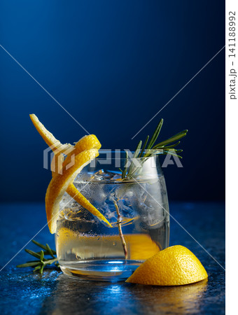 Gin and tonick cocktail in a fogged up glass on a dark blue background. Gin and tonick cocktail in a fogged up glass on a dark blue background. 141188992