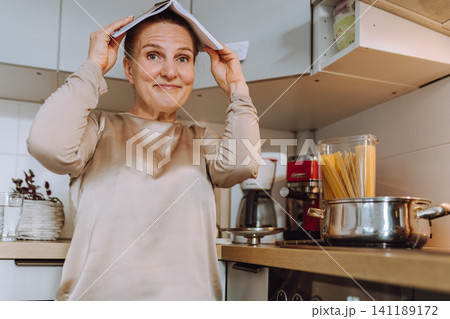 middle-aged woman prepares a recipe for lunch in her home kitchen 141189172