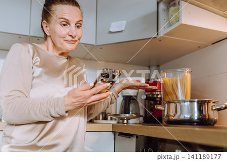 middle-aged woman prepares a recipe for lunch in her home kitchen middle-aged woman prepares a recipe for lunch in her home kitchen 141189177